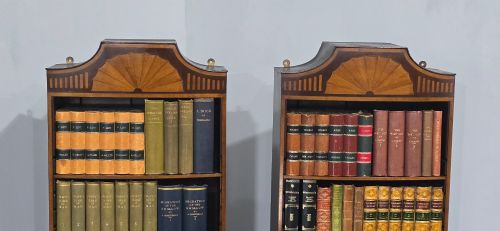 fig 1. A pair of tall slim mahogany open bookcases featuring inlaid fan pediments, adjustable shelves, and curved lower cupboard doors.
