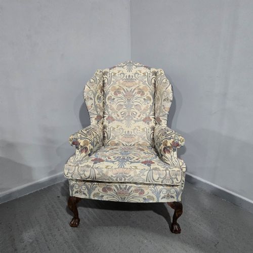 fig 1. A high-backed wing armchair upholstered in a botanical pattern fabric featuring dark mahogany cabriole front legs with carved ball and claw feet.