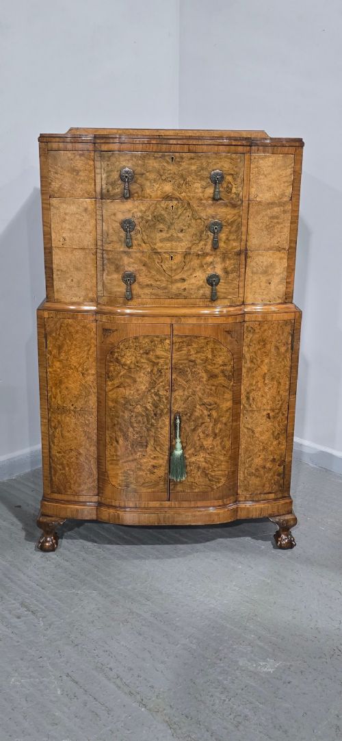 A two-section burr walnut linen press featuring a breakfront profile, upper drawers with drop handles, lower cupboard doors, and carved cabriole legs. View III