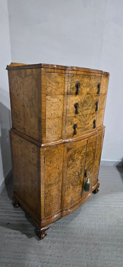 A two-section burr walnut linen press featuring a breakfront profile, upper drawers with drop handles, lower cupboard doors, and carved cabriole legs. View XIV