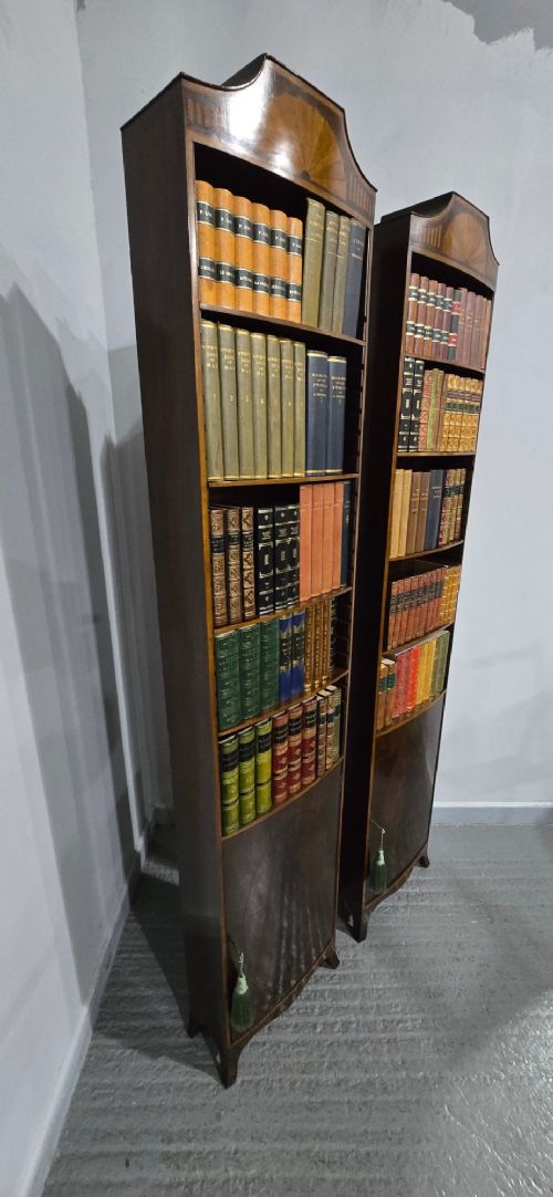 A pair of tall, narrow mahogany open bookcases featuring inlaid fan motifs at the arched top, adjustable shelves filled with books, and lower cupboard doors. View XI