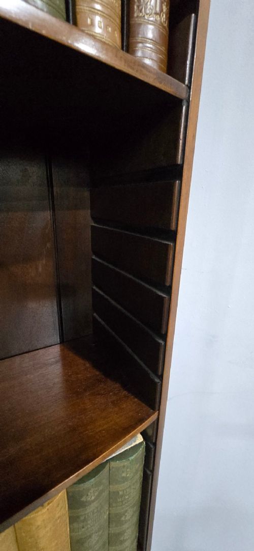 A pair of tall, narrow mahogany open bookcases featuring inlaid fan motifs at the arched top, adjustable shelves filled with books, and lower cupboard doors. View XII