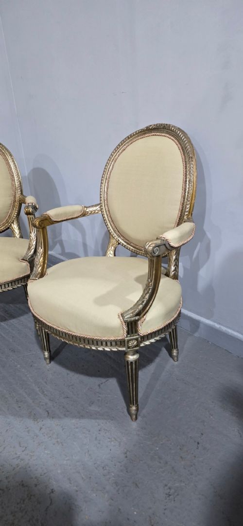 A pair of French Louis XVI style open armchairs featuring carved giltwood frames with oval medallion backs, fluted legs, and neutral cream upholstery. View VII
