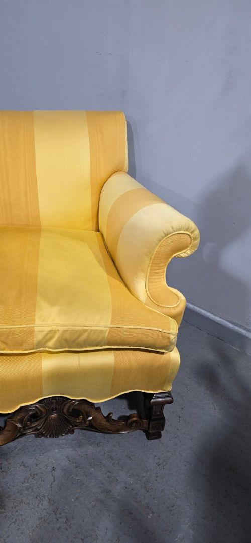 An upholstered sofa featuring yellow and gold vertical stripes with an intricately carved dark oak base decorated with shell motifs and scrolls. View IX