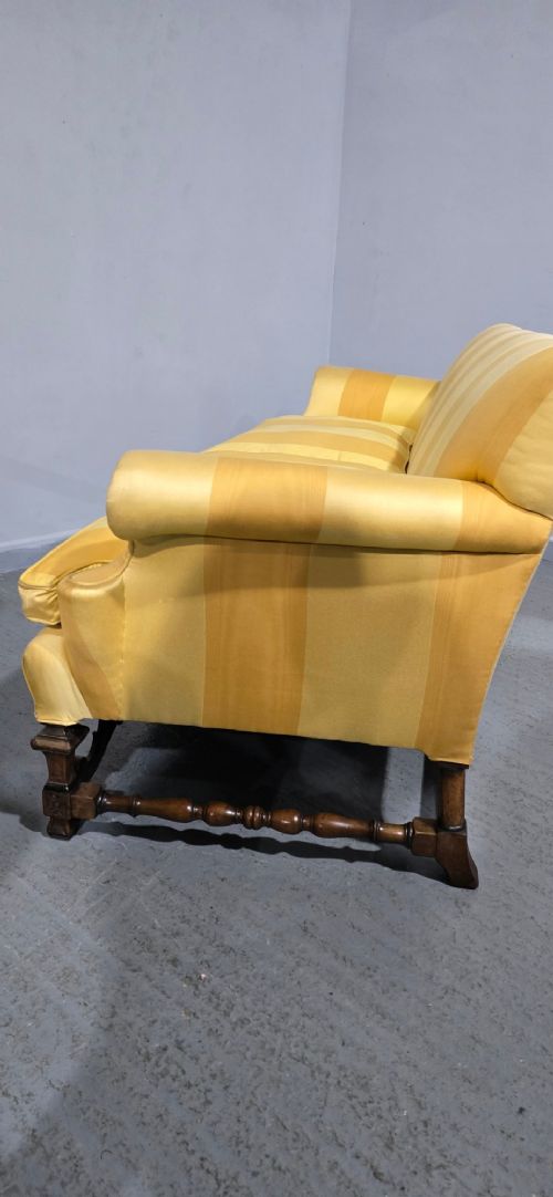 An upholstered sofa featuring yellow and gold vertical stripes with an intricately carved dark oak base decorated with shell motifs and scrolls. View X