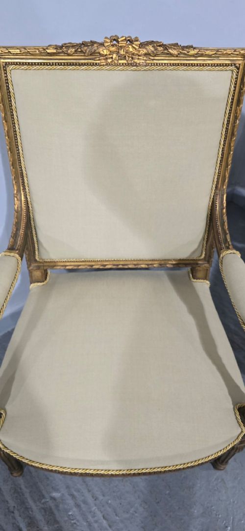 A pair of French Neoclassical giltwood open armchairs upholstered in neutral fabric with fluted tapered legs and carved square backs. View VIII