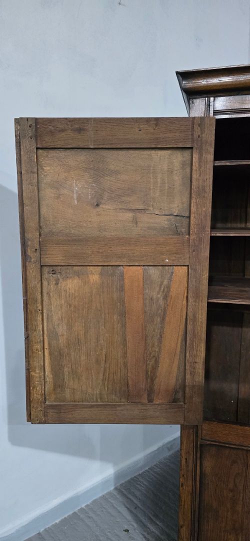 A tall, narrow antique dark oak food cupboard featuring panelled doors, hand-forged iron hinges, a metal ring drop handle, and a top moulded cornice. View VIII
