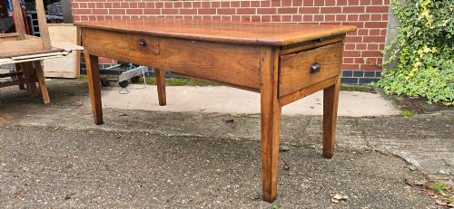 fig 1. A rectangular French cherry wood refectory dining table featuring a three-plank top, side frieze drawer with metal handle, and square tapered legs.