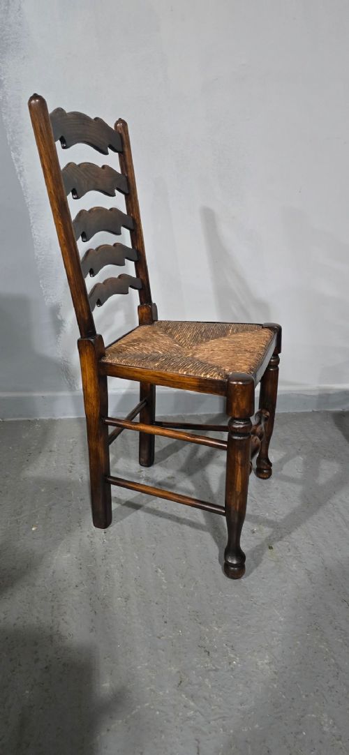 A set of twelve dark oak ladder back dining chairs featuring woven rush seats, shaped horizontal back slats, and turned front legs. View VIII