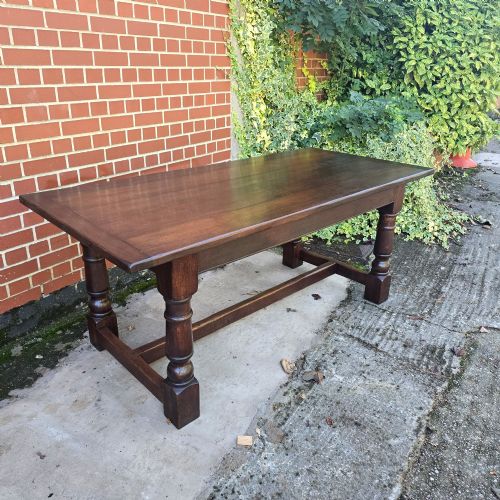 fig 1. A solid dark oak refectory dining table with a plank top, stout turned legs, and an H-stretcher base.