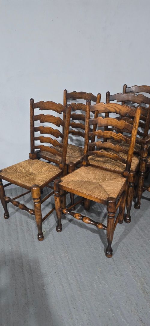 A set of twelve oak dining chairs featuring shaped ladder back slats, natural rush seats, and turned front legs. View IV