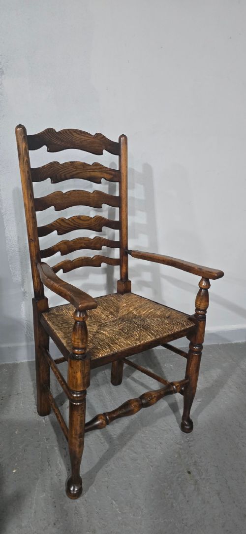 A set of twelve oak dining chairs featuring shaped ladder back slats, natural rush seats, and turned front legs. View XII