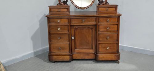 fig 1. A Victorian mahogany dressing table featuring a central oval swivelling mirror, carved scroll supports, small upper trinket drawers, and twin drawer pedestals flanking a central cupboard.