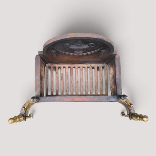 fig 1. An Adam style fireplace dog grate crafted from cast iron and brass, featuring a serpentine pierced apron, urn finials, and a relief urn backplate.