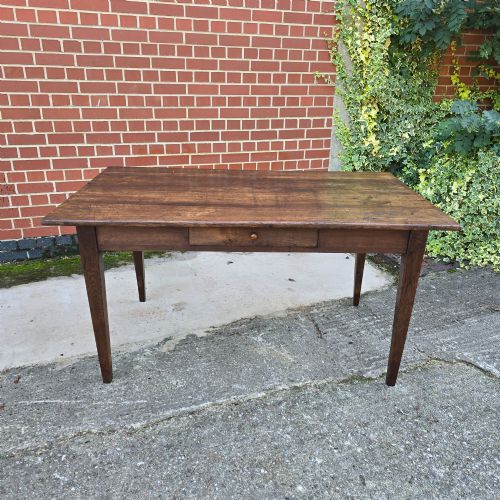 fig 1. A rectangular rustic oak dining table featuring a frieze drawer with a wooden knob and four square tapered legs.