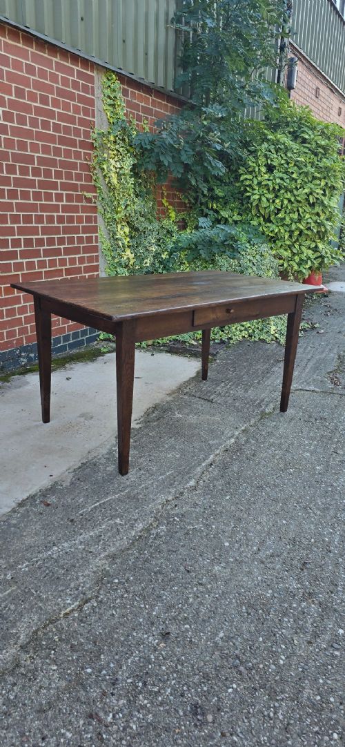 A rectangular rustic oak dining table featuring a frieze drawer with a wooden knob and four square tapered legs. View V