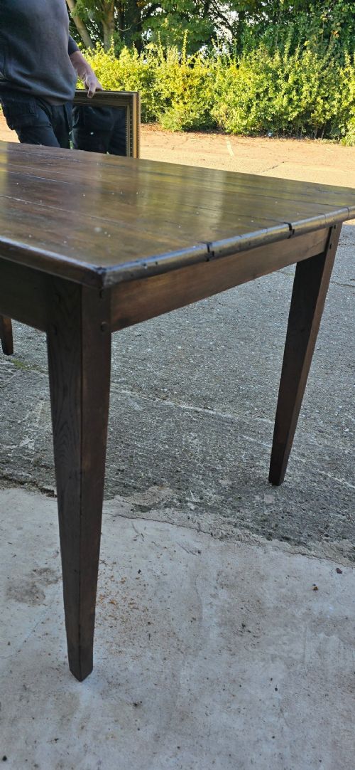 A rectangular rustic oak dining table featuring a frieze drawer with a wooden knob and four square tapered legs. View XIII
