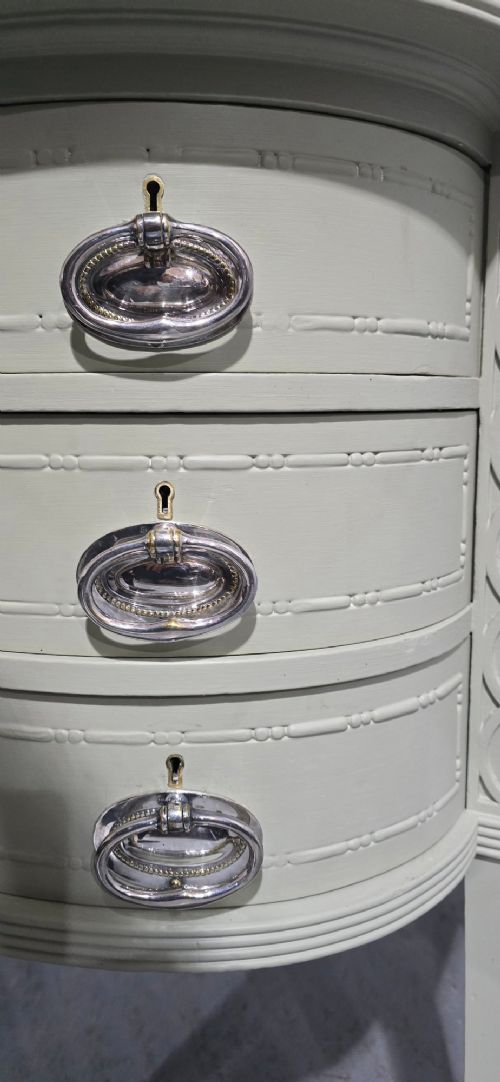 A sage green painted dressing table featuring an integrated central shield mirror, side trinket drawers, metal scroll sconces, and tapered legs. View VII
