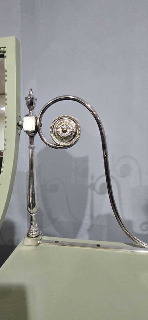 A sage green painted dressing table featuring an integrated central shield mirror, side trinket drawers, metal scroll sconces, and tapered legs. View XII