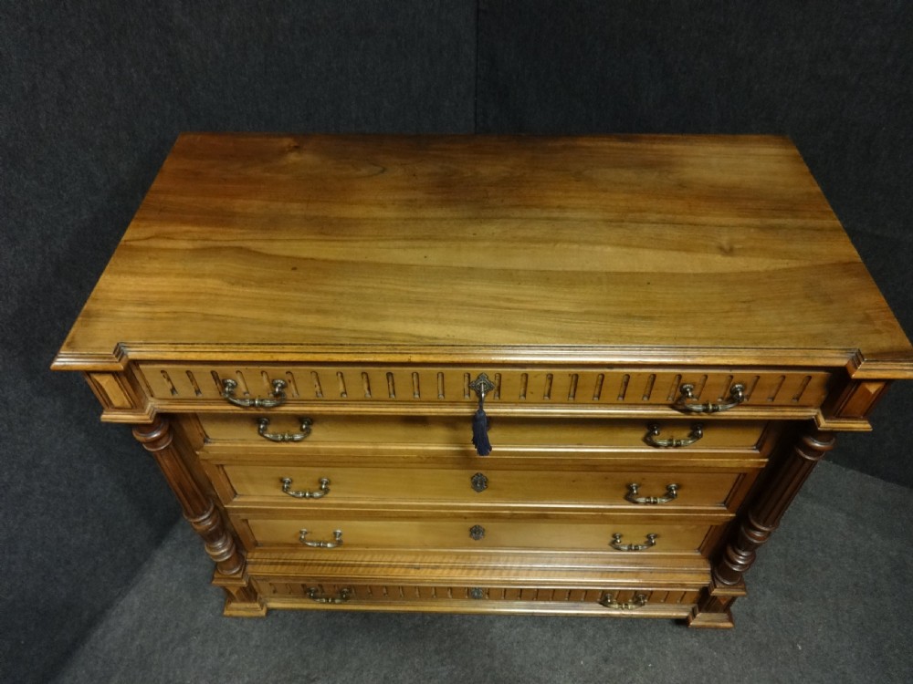 A French walnut chest of drawers featuring five drawers with brass handles, fluted carved top and bottom panels, and turned side columns. View VIII