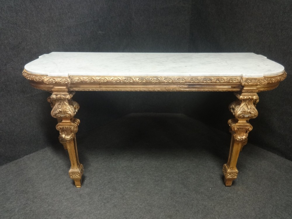 A Regency period giltwood console table featuring carved scroll support legs and a white marble top. View X