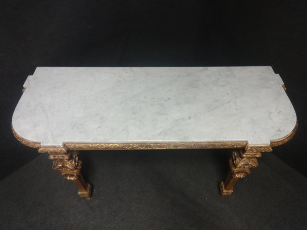A Regency period giltwood console table featuring carved scroll support legs and a white marble top. View XII