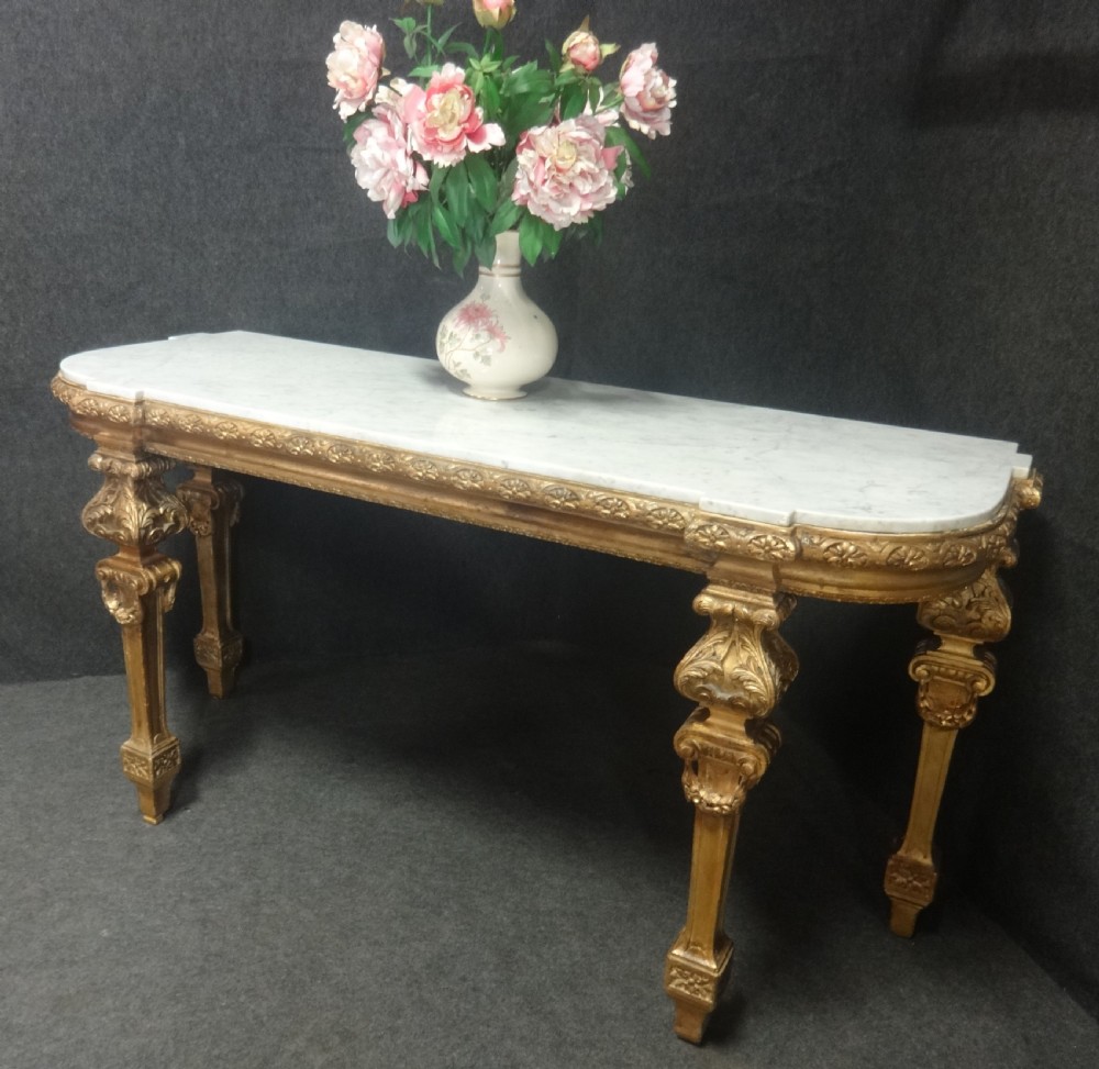 A Regency period giltwood console table featuring carved scroll support legs and a white marble top. View XV