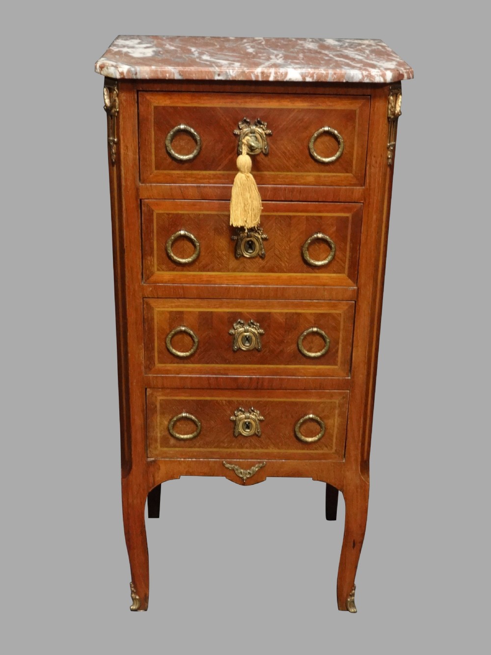 A tall French tulipwood chest featuring four drawers with geometric parquetry inlay, brass ring handles, cabriole legs, and a fitted marble top.