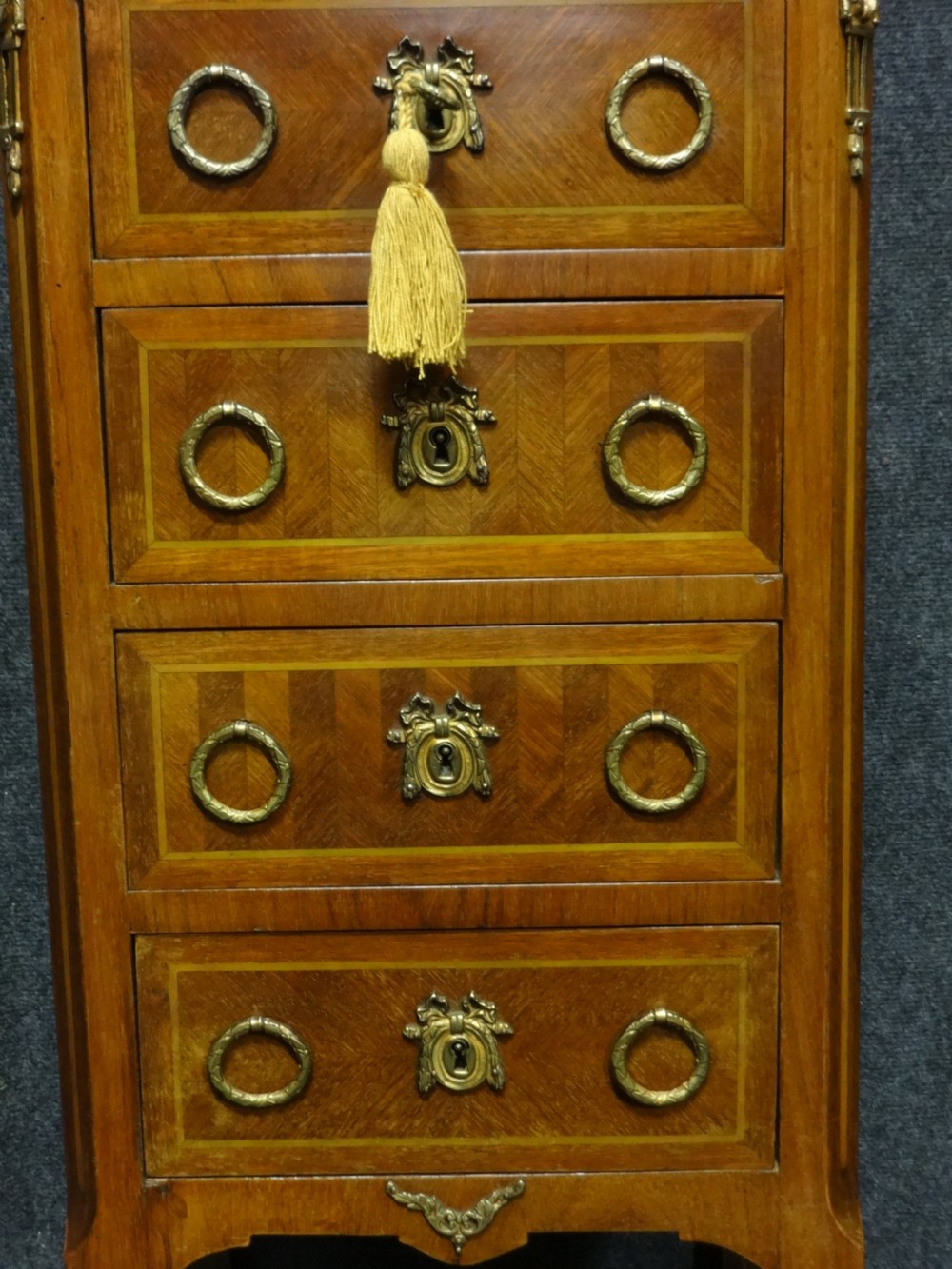 A tall French tulipwood chest featuring four drawers with geometric parquetry inlay, brass ring handles, cabriole legs, and a fitted marble top. View II