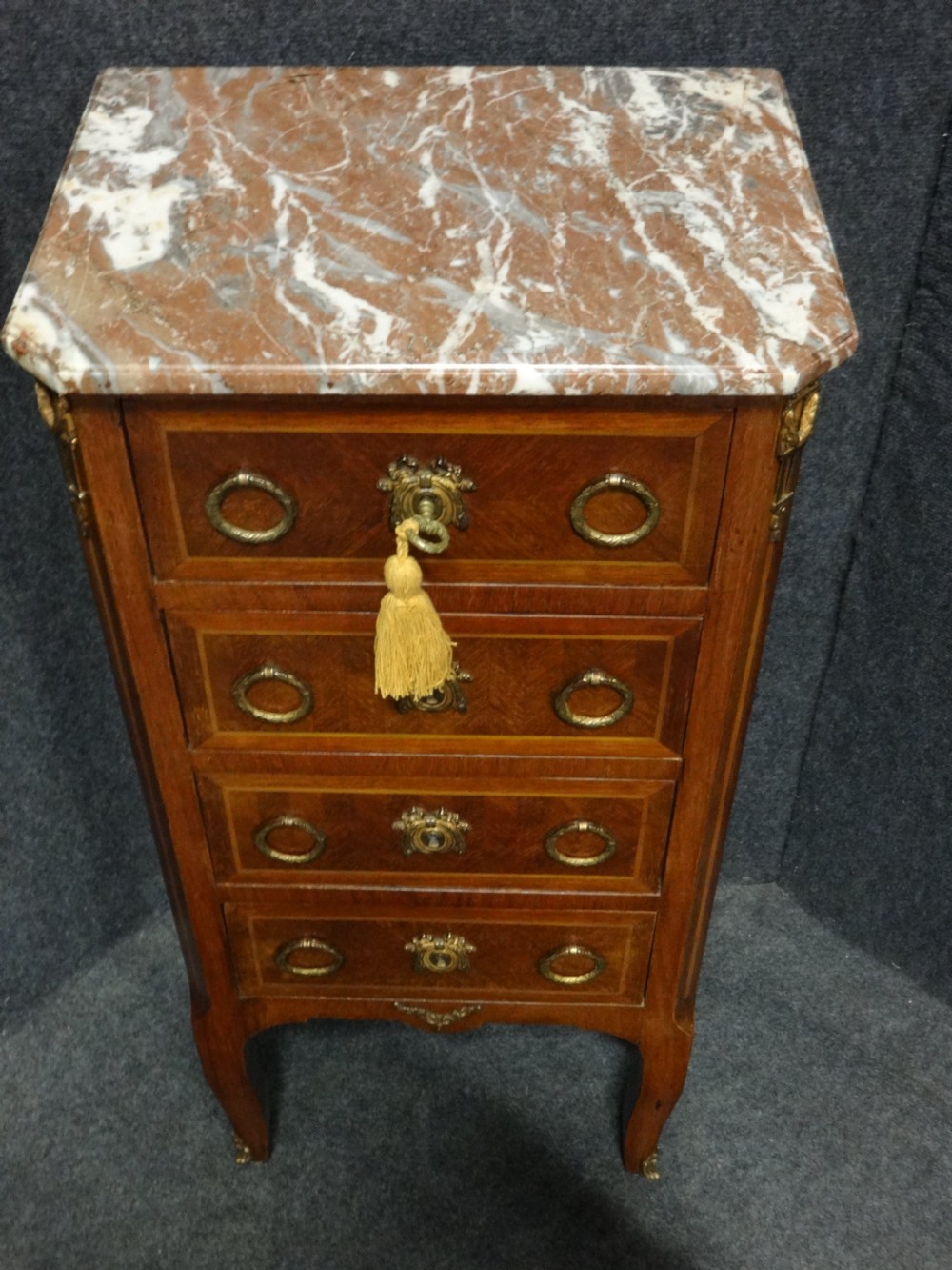 A tall French tulipwood chest featuring four drawers with geometric parquetry inlay, brass ring handles, cabriole legs, and a fitted marble top. View VI