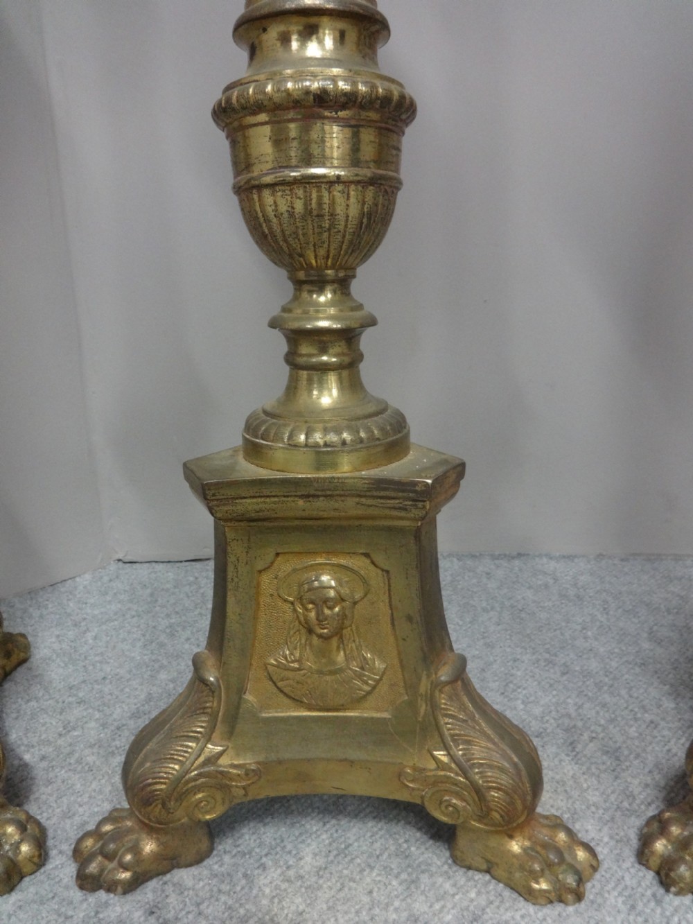 A set of four tall French brass church candlesticks featuring fluted columns, tri-form bases with relief portraits, and claw feet. View II