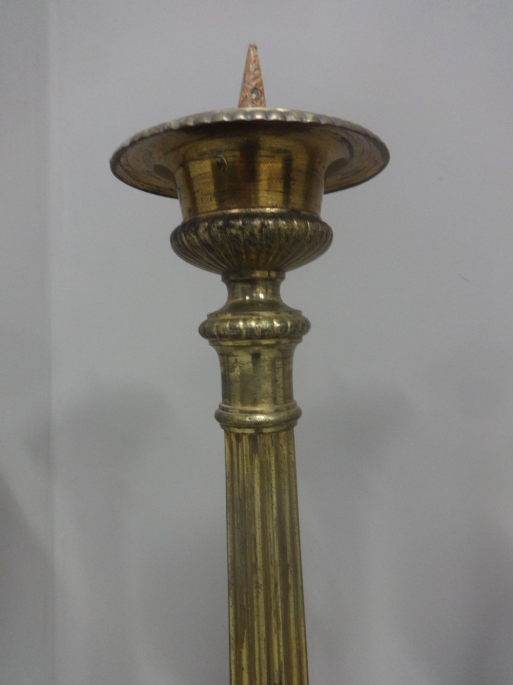 A set of four tall French brass church candlesticks featuring fluted columns, tri-form bases with relief portraits, and claw feet. View IV