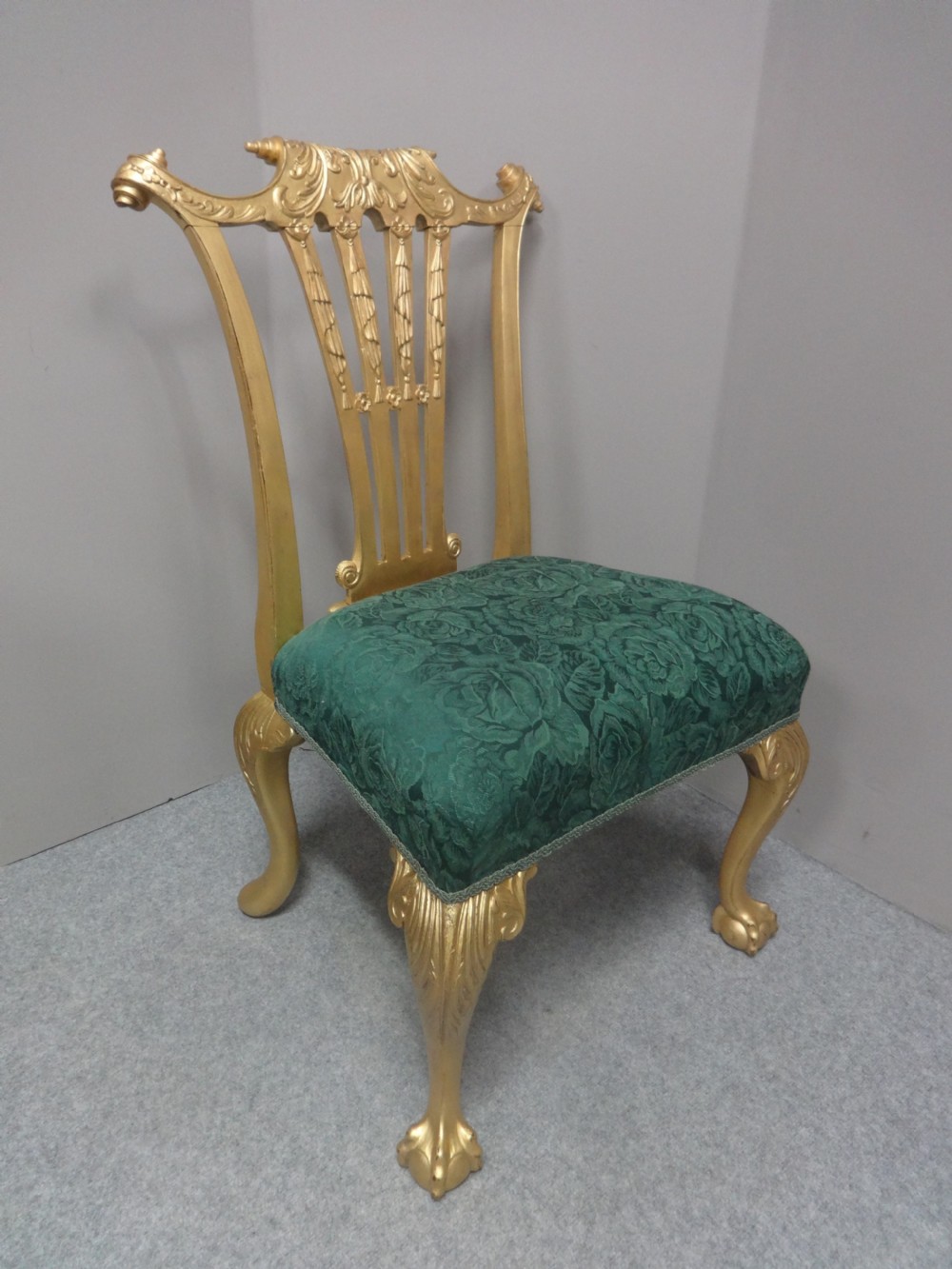 A Georgian giltwood side chair featuring carved cabriole legs with claw and ball feet, an ornate pierced splat back, and green patterned upholstery.