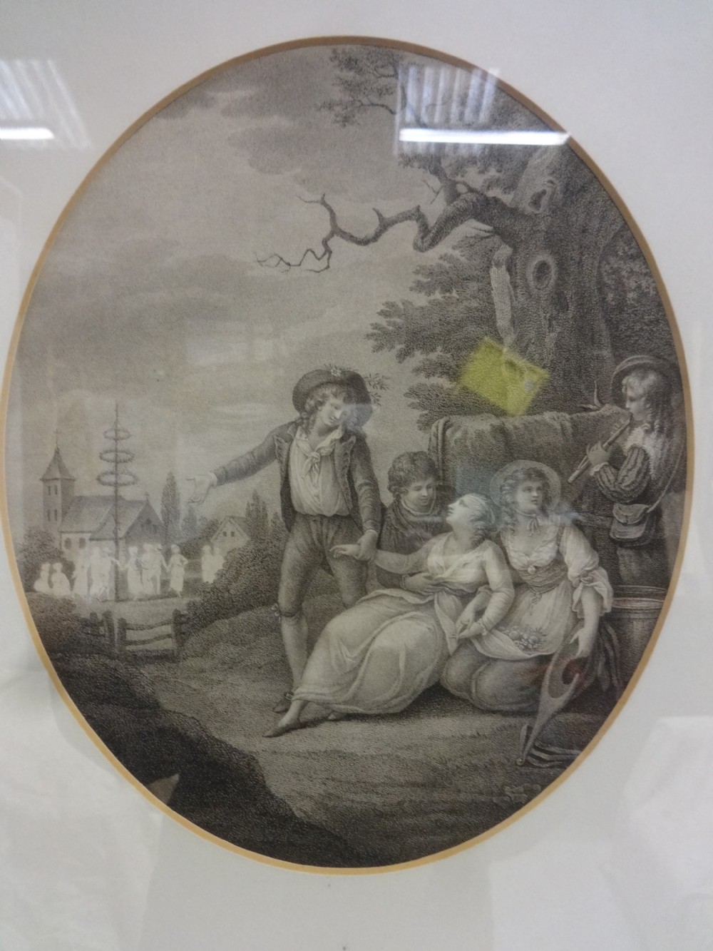 A framed antique print depicting a figurative pastoral scene set inside an oval aperture with a black frame and gilt inner trim. View II