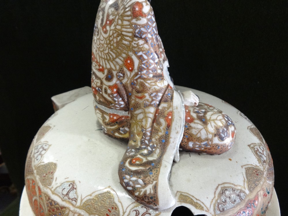 An antique Japanese Satsuma ceramic koro incense burner featuring tripodic legs, side handles, hand-painted figures, gold embellishments, and a seated figure finial on the lid. View XV