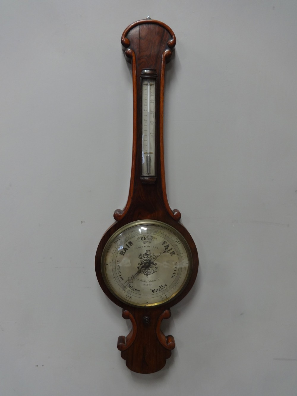 A nineteenth-century rosewood wheel mercury barometer with a brass-trimmed silvered dial and an integrated thermometer tube.