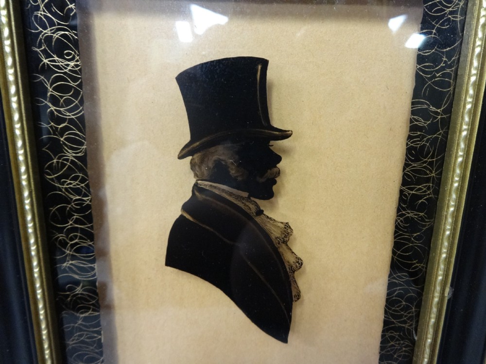 A framed 19th-century profile silhouette of a gentleman wearing a top hat, presented within a gilded glass mount and ebonised frame. View II