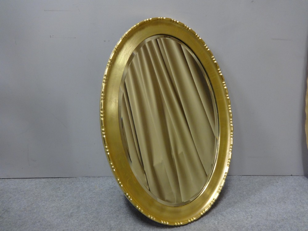 An oval Edwardian wall mirror with a gilded frame featuring beaded trim details around a bevelled glass mirror plate. View II