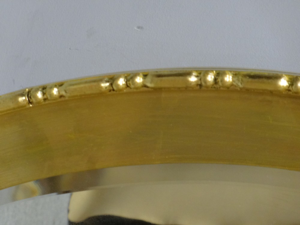 An oval Edwardian wall mirror with a gilded frame featuring beaded trim details around a bevelled glass mirror plate. View IV