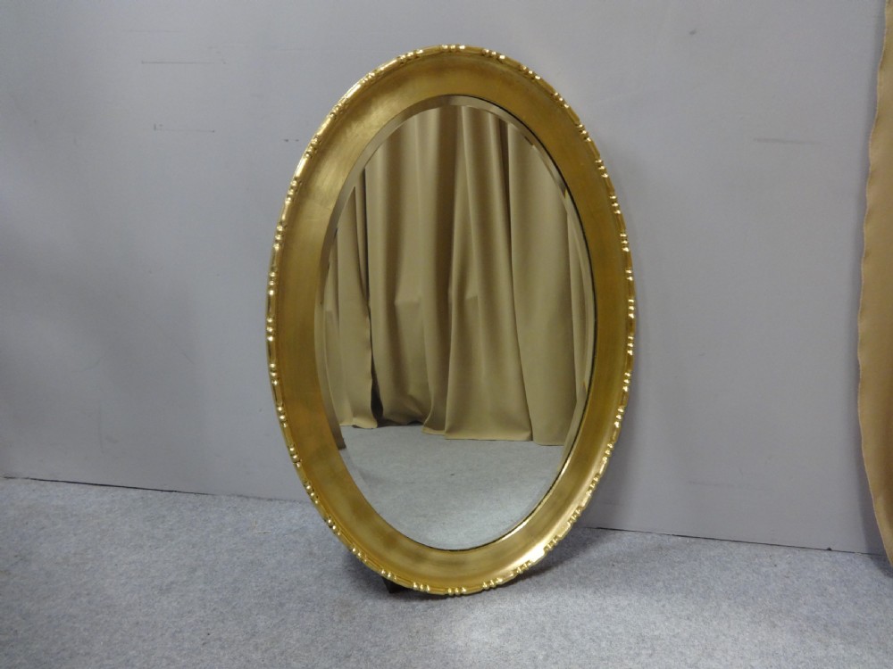 An oval Edwardian wall mirror with a gilded frame featuring beaded trim details around a bevelled glass mirror plate. View VI