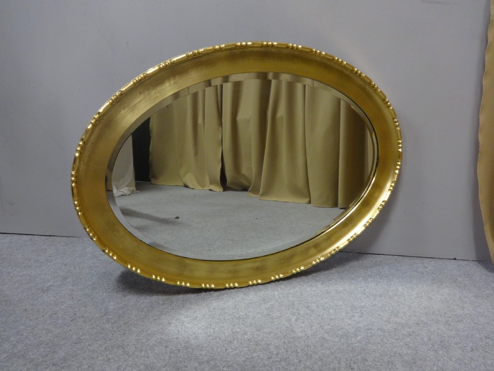An oval Edwardian wall mirror with a gilded frame featuring beaded trim details around a bevelled glass mirror plate. View IX