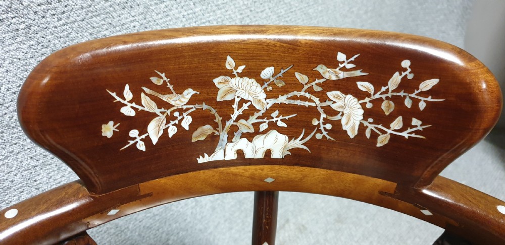 A pair of warm brown hardwood Chinese corner chairs featuring intricate mother-of-pearl floral inlays and carved pierced back splats. View X