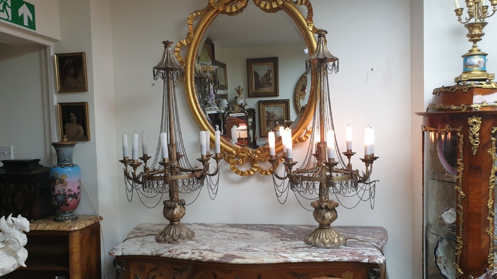 A pair of tall giltwood and metal eight-branch French candelabra table lamps featuring hanging wire swags and a tented canopy top.