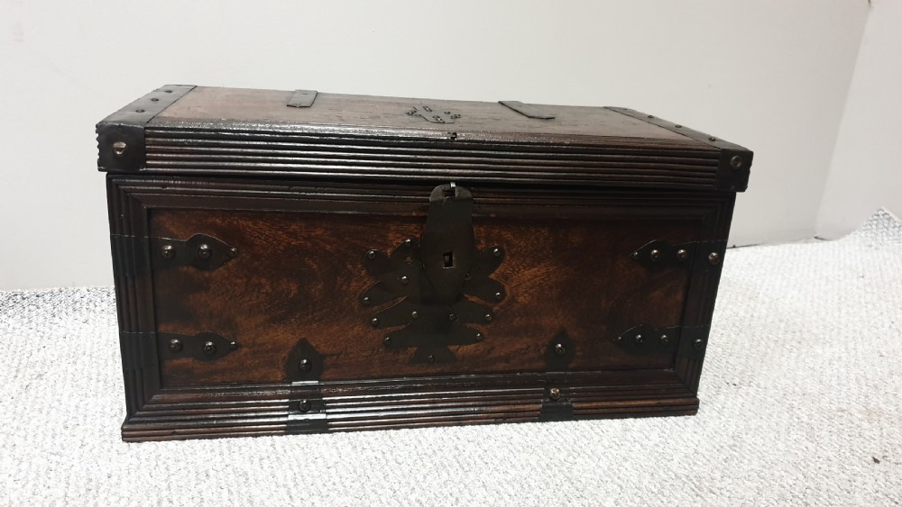 A dark mahogany wooden chest featuring decorative forged iron strapwork, corner brackets, and a central iron escutcheon plate. View II