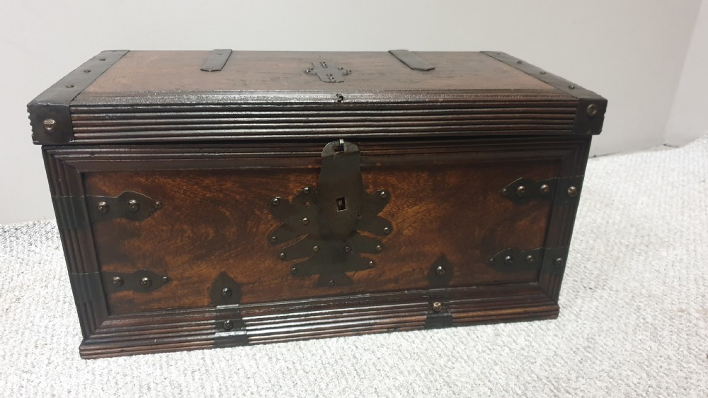 A dark mahogany wooden chest featuring decorative forged iron strapwork, corner brackets, and a central iron escutcheon plate. View III