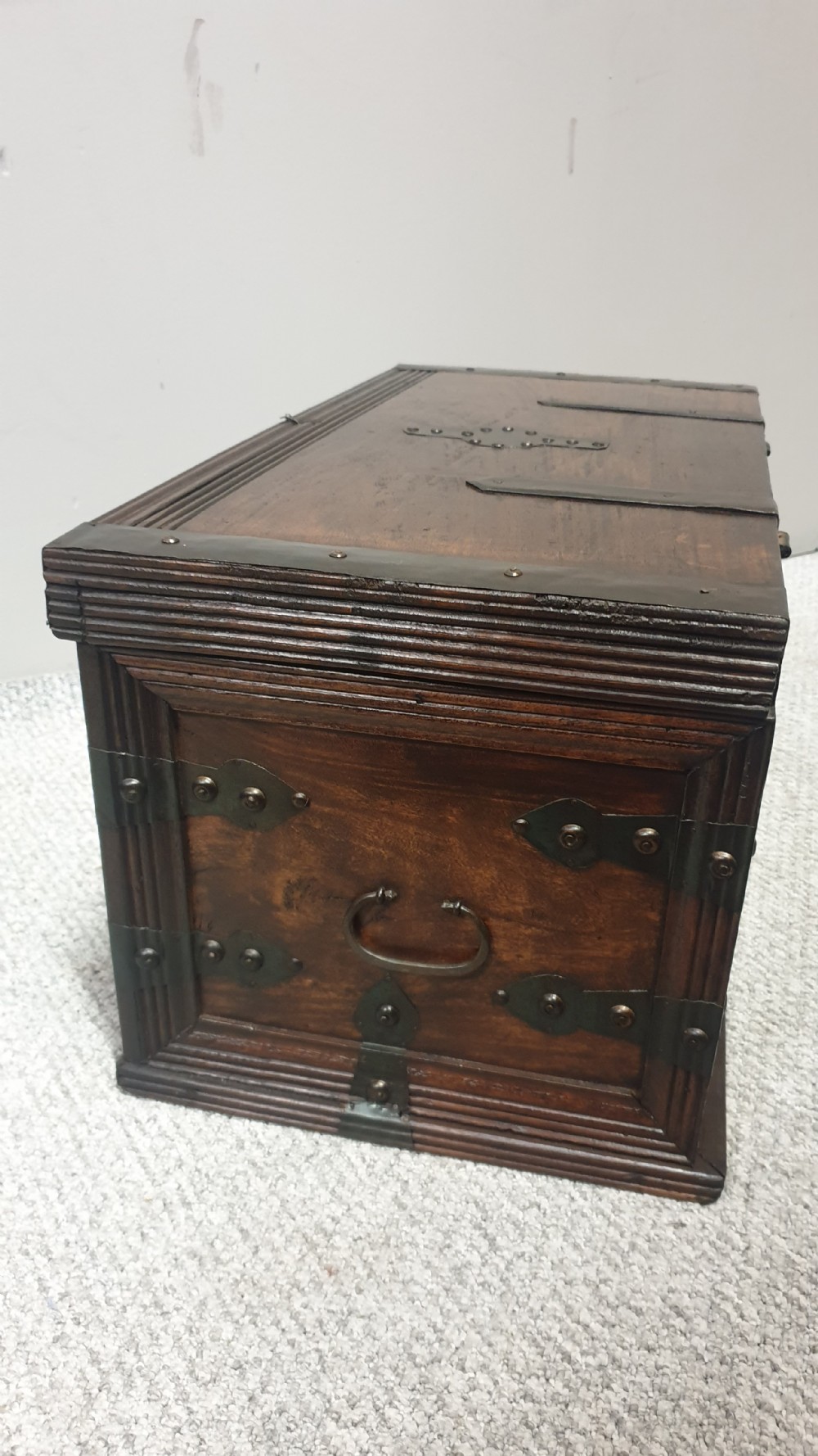 A dark mahogany wooden chest featuring decorative forged iron strapwork, corner brackets, and a central iron escutcheon plate. View VIII