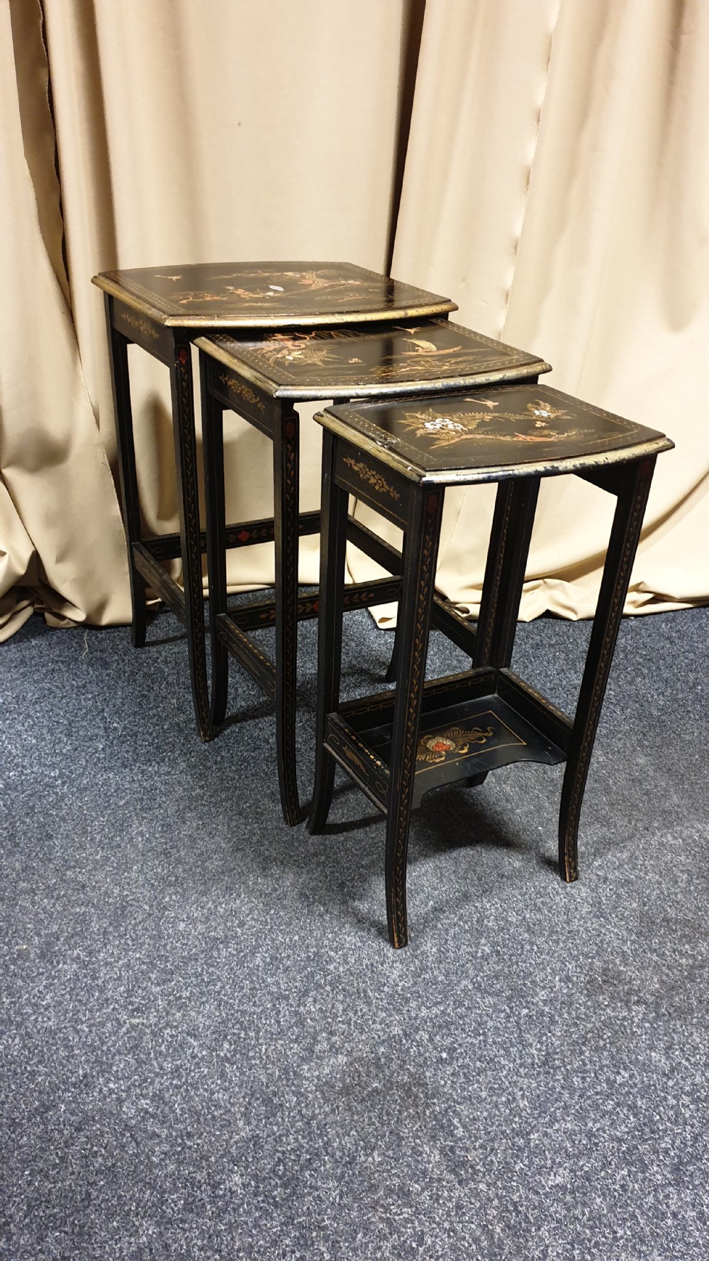 A set of three black lacquered Chinoiserie nesting tables decorated with gilded landscapes and shell inlay. View II
