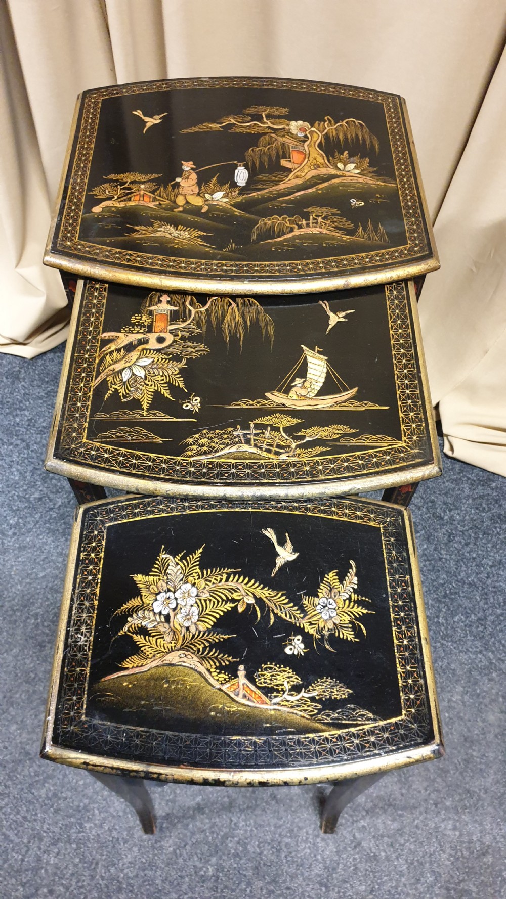 A set of three black lacquered Chinoiserie nesting tables decorated with gilded landscapes and shell inlay. View III