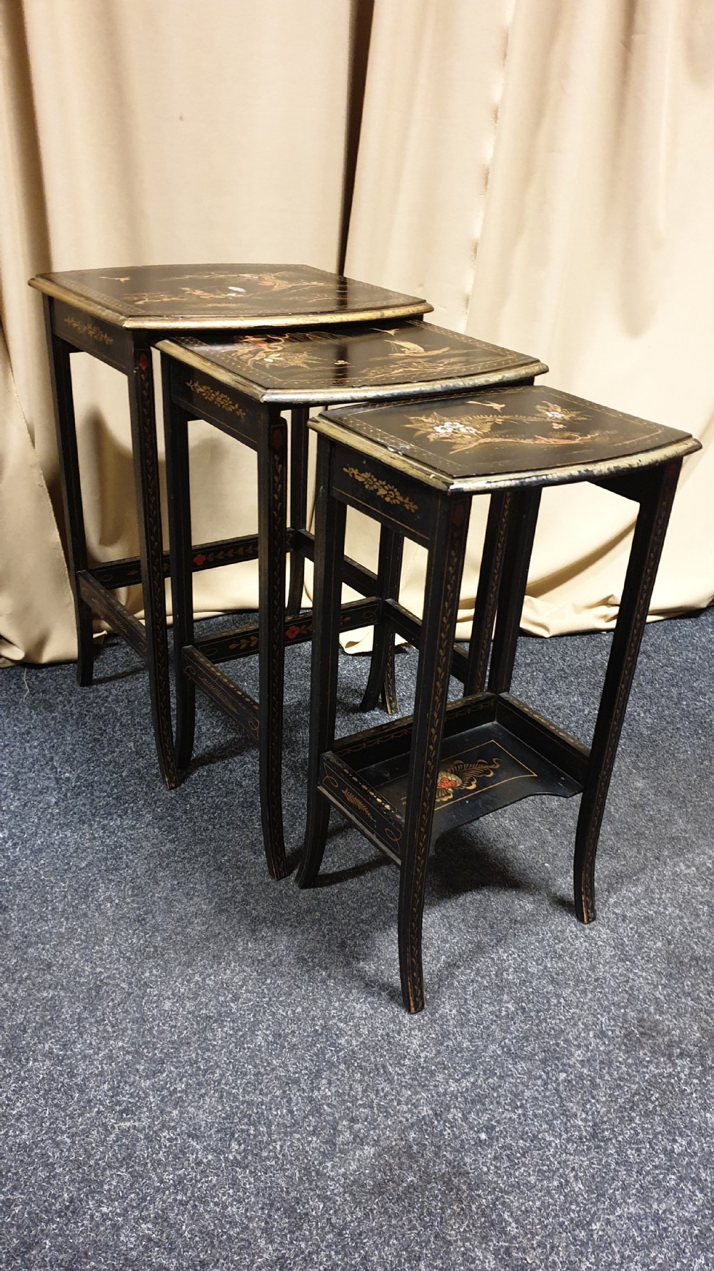 A set of three black lacquered Chinoiserie nesting tables decorated with gilded landscapes and shell inlay. View V