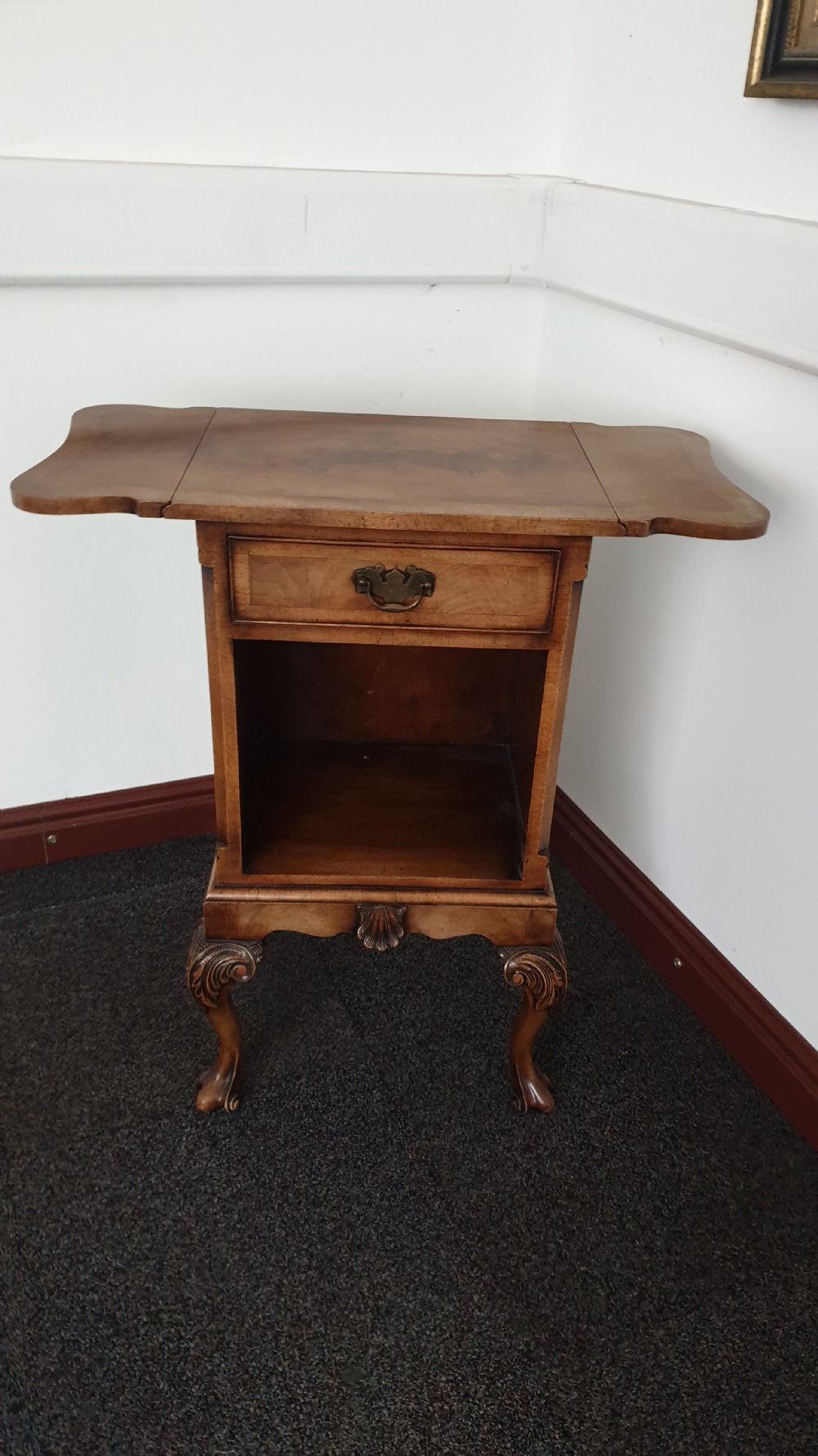 A Queen Anne style walnut bedside cabinet featuring side drop flaps, a single drawer over an open compartment, a carved shell apron, and cabriole legs. View II